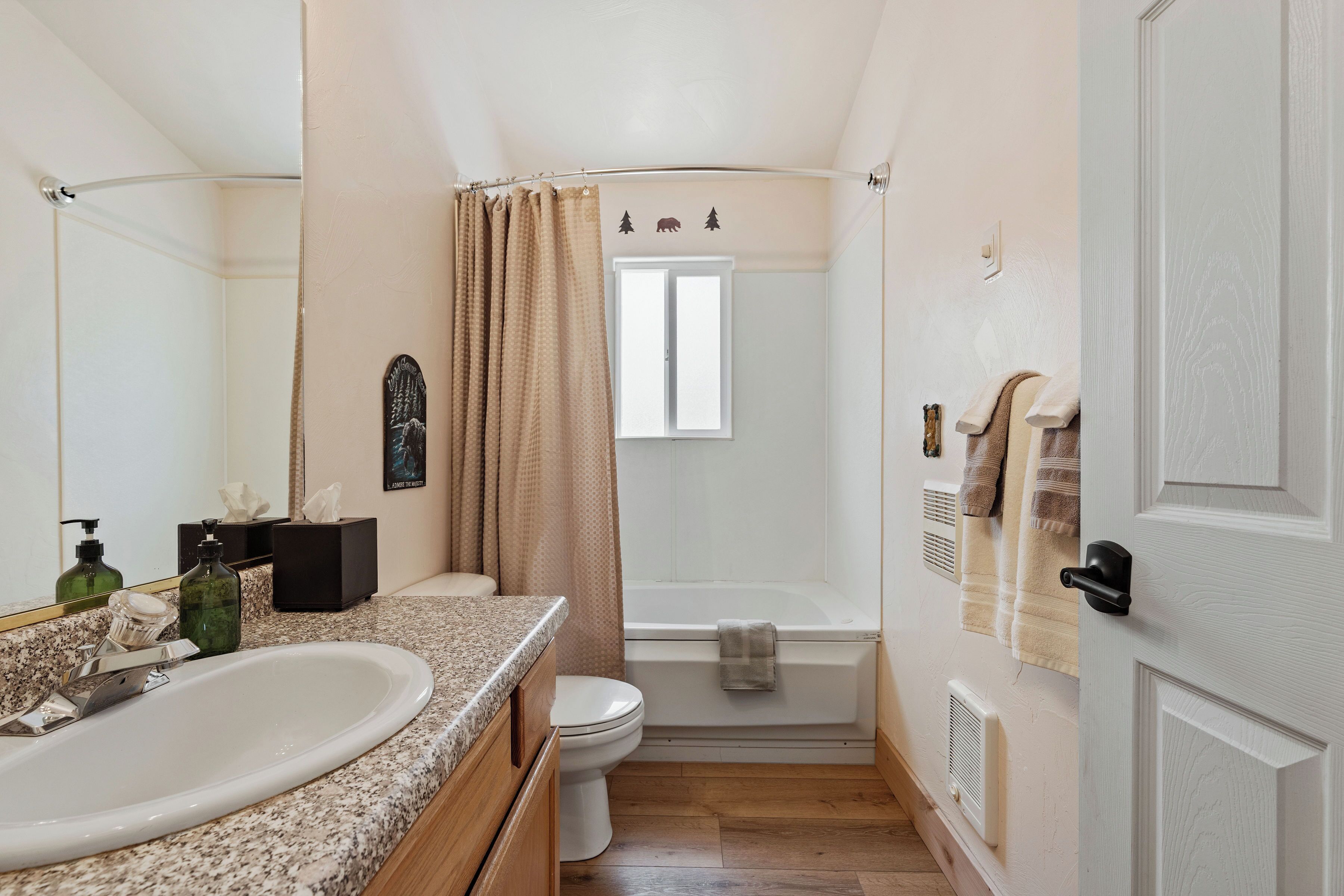 A bathroom with a sink, toilet, bathtub, and a shower curtain.