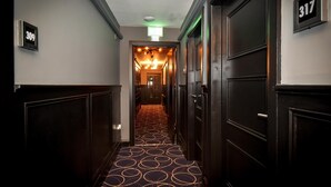 A hallway with dark wood paneling, a patterned carpet, and a ceiling light fixture. - The Lane - Boutique Residence (Galway)