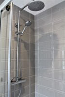 Ducha con cabezal de ducha de mano y panel de control en la pared.