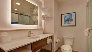 A modern bathroom with a large mirror, white sink, wooden vanity, and a toilet.