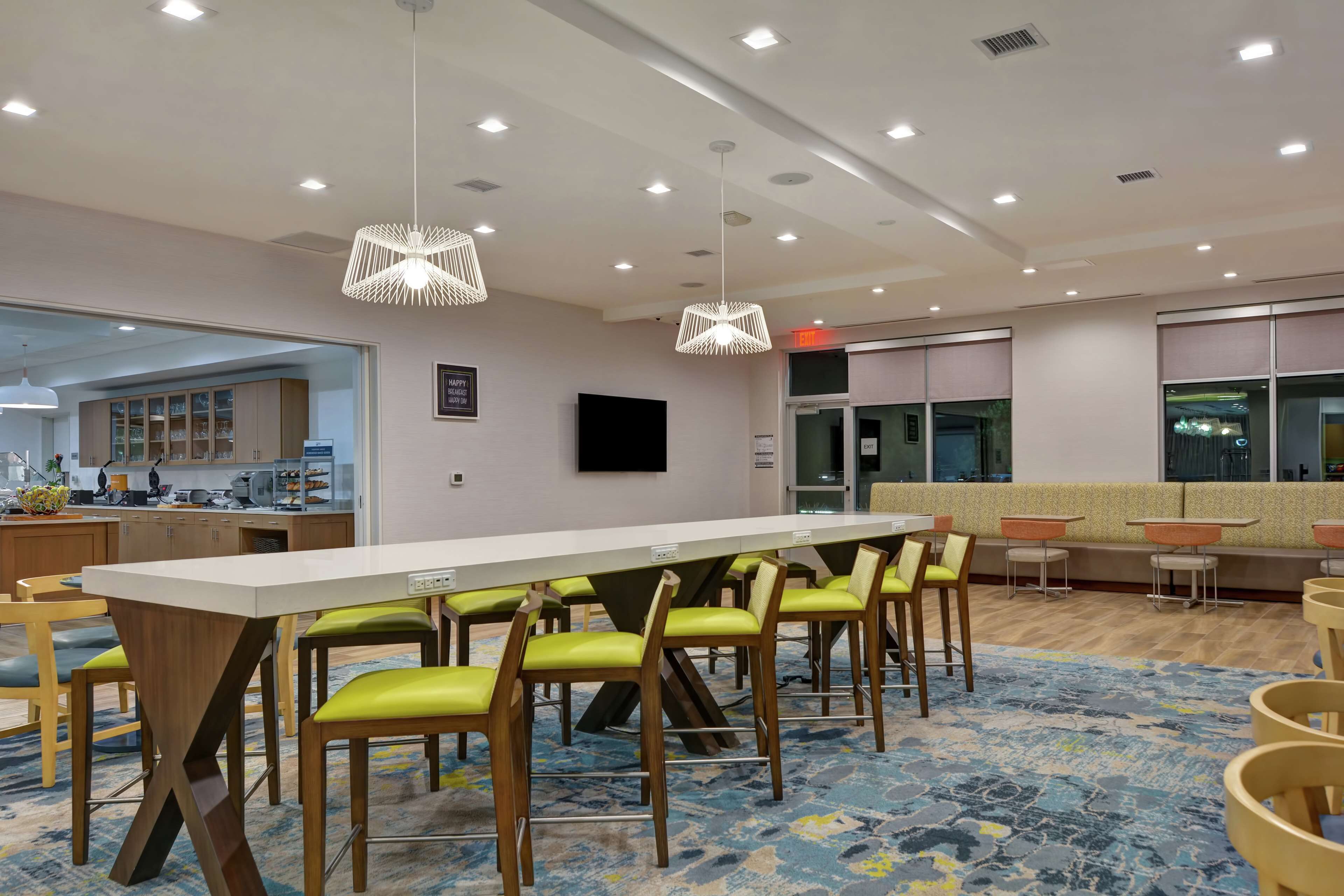 A modern conference room with a long table, green chairs, and a patterned carpet.