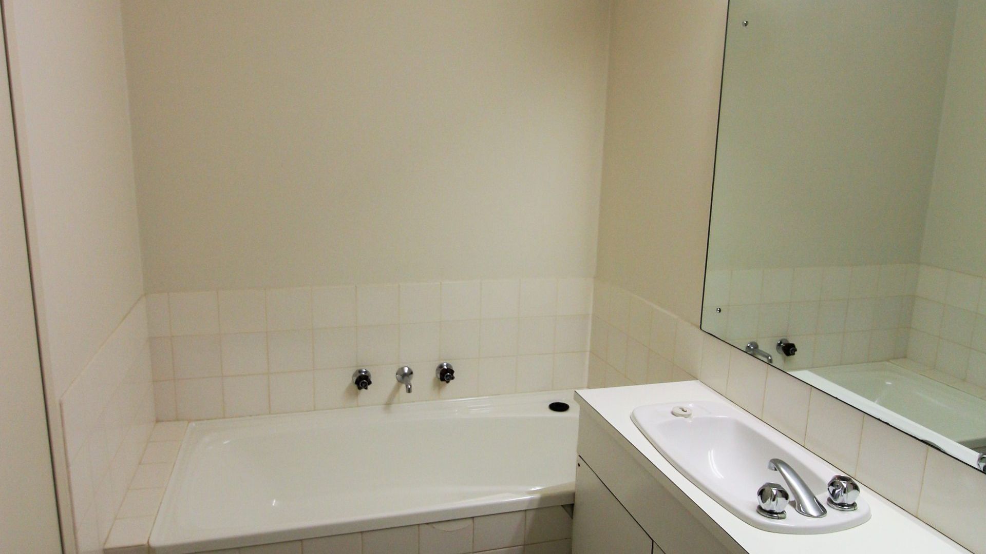 A bathroom with a bathtub, a sink, and a mirror.