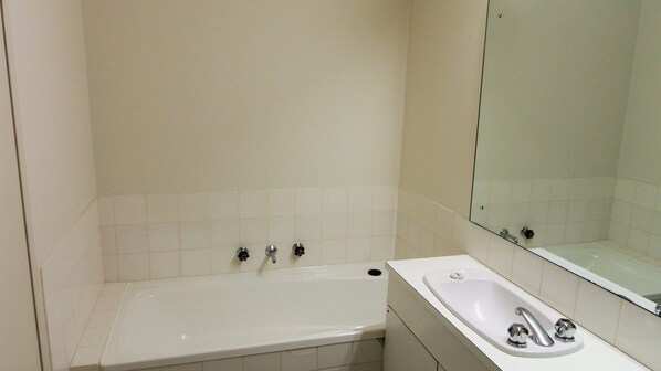 A bathroom with a bathtub, a sink, and a mirror.