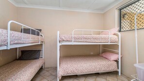 A bunk bed room with a window and a small trash bin. - Ocean Court 8, 13 Lord Street (Port Macquarie)