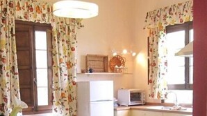 Una cocina compacta con una mesa, sillas, un refrigerador, un microondas y un lavamanos.