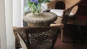 Un comedor con sillas de mimbre, una mesa redonda con un jarrón de flores y una lámpara.