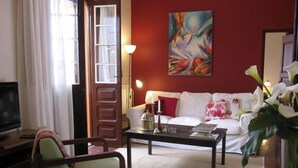 Una sala de estar con un sofá blanco, una mesa de centro de madera y un sillón verde.