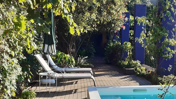 Zona de piscina con sillones de descanso y un jacuzzi.
