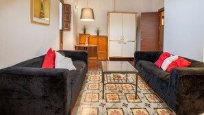 A living room with two black sofas, a patterned floor, a wooden cabinet, and a white wardrobe. - Historic apartment house with exceptional situation and kept facility (Granada)
