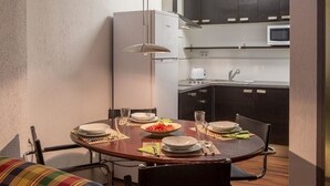 A compact kitchen with dark cabinets, a microwave, and a refrigerator. - Historic apartment house with exceptional situation and kept facility (Granada)
