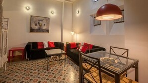 A cozy living room with a sofa, a glass table, and a red lamp. - Historic apartment house with exceptional situation and kept facility (Granada)