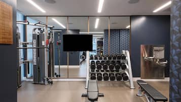 Een moderne sportschool met trainingsapparatuur, een bank en een aan de muur bevestigde televisie.