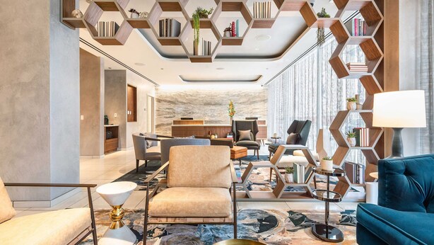 Una sala de estar moderna con un sofá, sillones, una mesa de centro y una estantería.