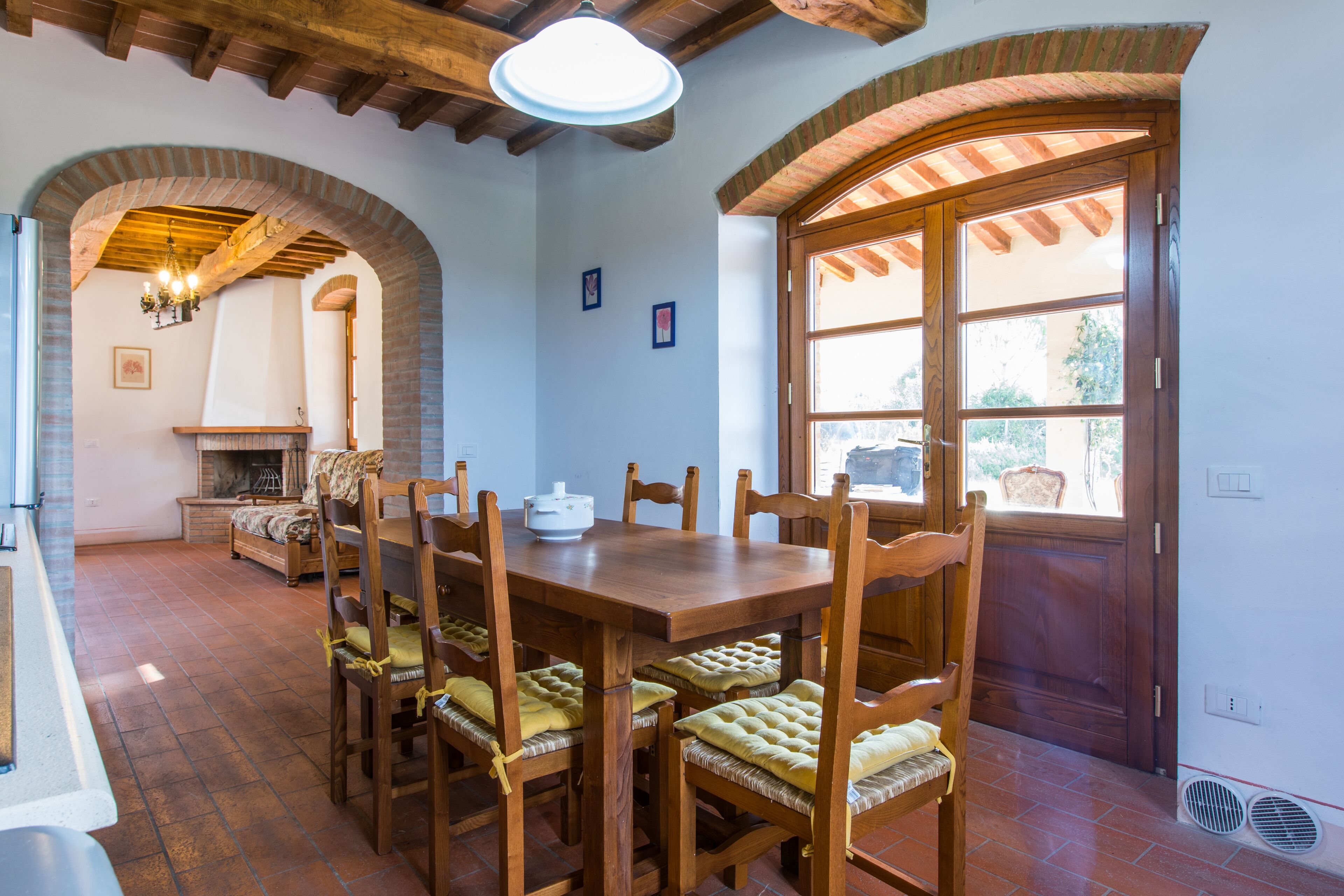 Un coin repas avec une table et des chaises en bois, une cheminée et une grande fenêtre.