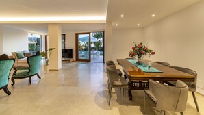 A spacious dining area with a wooden table, cushioned chairs, and a potted plant. - Attaláya with swimming pool and garden (San Corrado di Fuori)