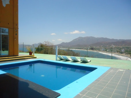 Una piscina al aire libre, sillones reclinables de piscina