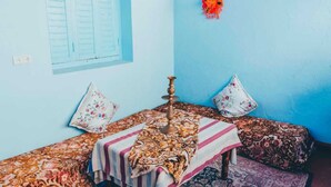 A room with a blue wall, a window with shutters, a patterned bedspread, and a decorative item on the wall. - Casa Karam With View Of The 3 Mountains (chefchaouen)
