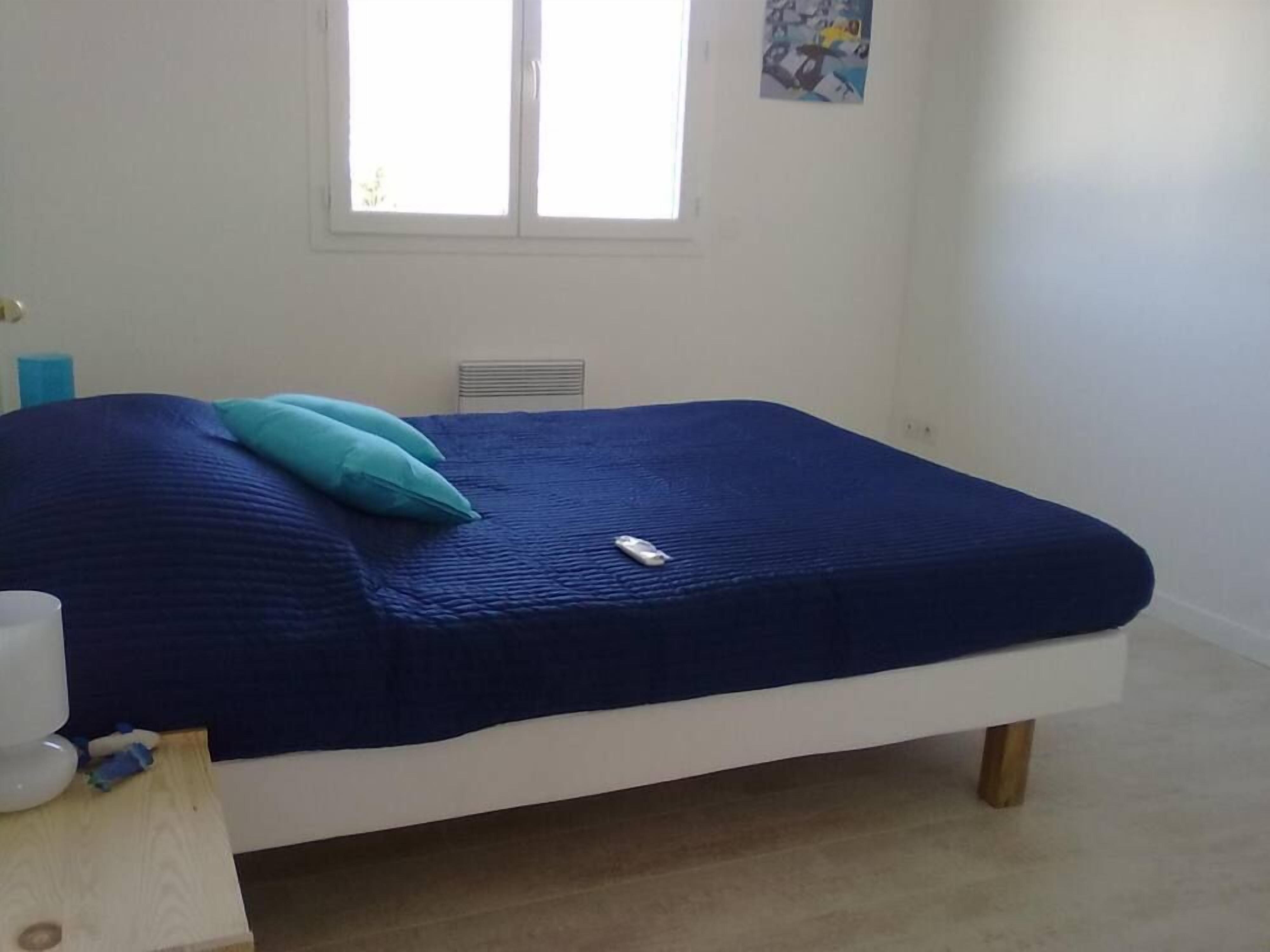 Ein Schlafzimmer mit Bett, Fenster und einem Bild an der Wand.