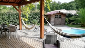 Eine Holzterrasse mit Korbmöbeln, einer Hängematte und einem Pool.
