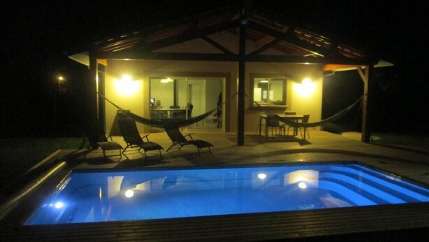 Ein Pool mit Liegestühlen und einer überdachten Sitzgelegenheit bei Nacht.