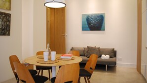 A dining area with a round table, chairs, a lamp, a book, and a painting on the wall. - Art Aldebaran: a magical feeling in the City Center with A/C! (VI. kerület)