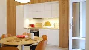 A modern kitchen with white cabinets, a dining table with chairs, and a glass door. - Art Aldebaran: a magical feeling in the City Center with A/C! (VI. kerület)