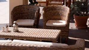 An outdoor patio with wicker furniture, stone pillars, and potted plants. - luxury villa,Mesinnia,penthouse sea view, family,reunions,swimming pool,leisure  (Messini)