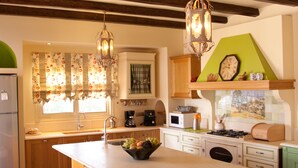 A kitchen with a large island, wooden stools, a hanging light fixture, and a clock on the wall. - luxury villa,Mesinnia,penthouse sea view, family,reunions,swimming pool,leisure  (Messini)