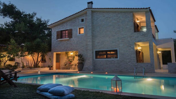 A two-story house with a swimming pool, outdoor seating, and a well-lit entrance. - Villa Corina near the Athens airport (Attica)