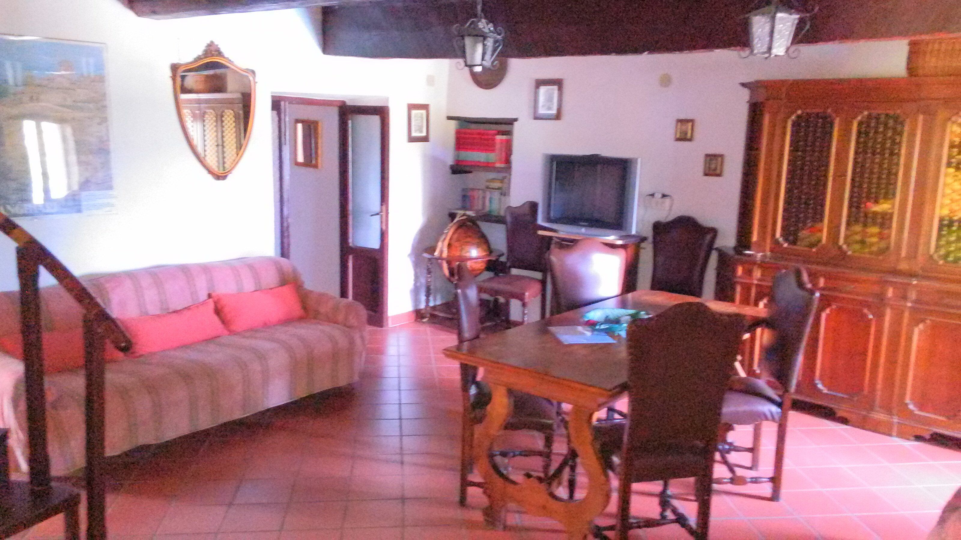 A living room with a sofa, dining table, chairs, a television, and a cabinet.