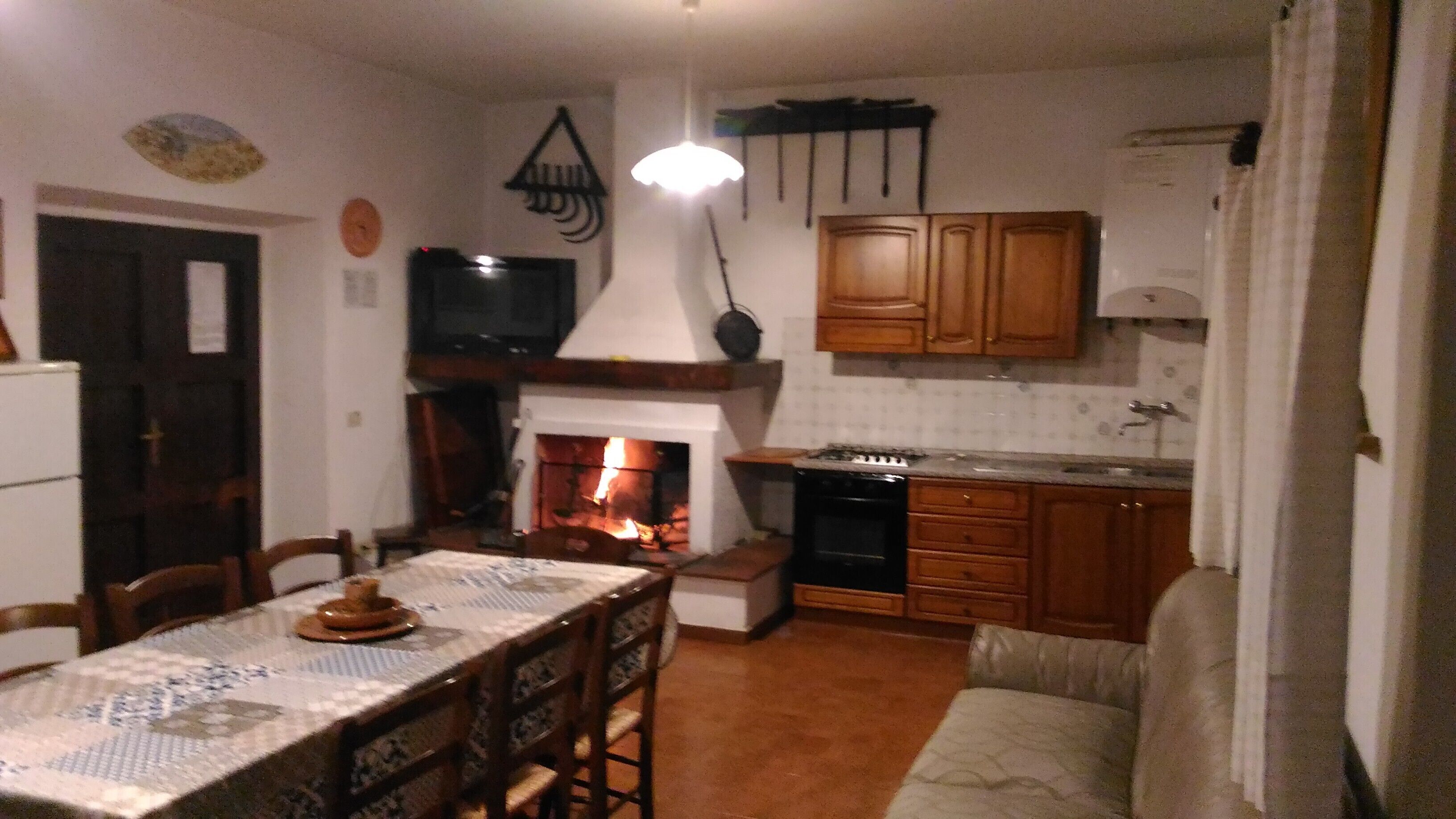 Un accogliente soggiorno con camino, mobili in legno, un tavolo da pranzo e una TV.