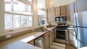 A modern kitchen with a dishwasher, oven, microwave, and stainless steel refrigerator.