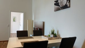 A modern dining area with a white table, black chairs, a potted plant, and a framed picture on the wall. - HAARDTER WINZER (Whg. 3) renovated and lovingly decorated "Pfalzcard-Partner" (Neustadt an der Weinstraße)