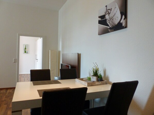 A modern dining area with a white table, black chairs, a potted plant, and a framed picture on the wall. - HAARDTER WINZER (Whg. 3) renovated and lovingly decorated "Pfalzcard-Partner" (Neustadt an der Weinstraße)
