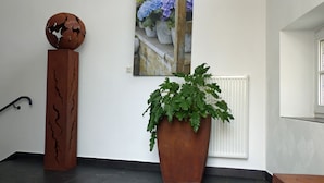 A room with a large potted plant, a globe sculpture, and a painting of flowers. - HAARDTER WINZER (Whg. 3) renovated and lovingly decorated "Pfalzcard-Partner" (Neustadt an der Weinstraße)