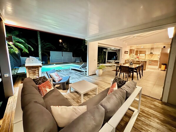 A modern living area with a pool, a dining area, and a kitchen.