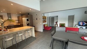 Een moderne keuken met een centraal eiland, barstoelen en een eethoek met tafel en stoelen.