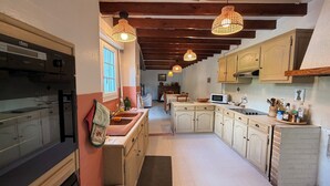 A kitchen with wooden cabinets, a sink, a microwave, and hanging pendant lights.