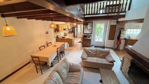 A spacious living area with a dining table, sofas, a fireplace, and a kitchen in the background.