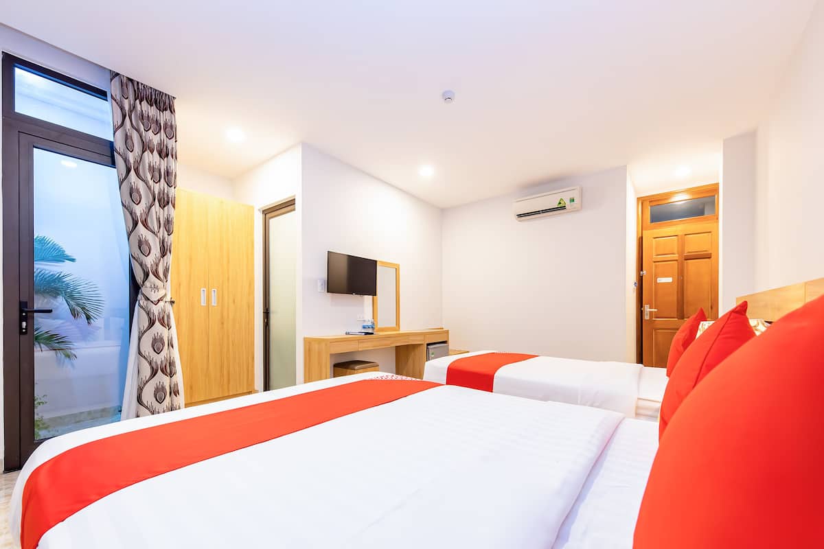 Ein Hotelzimmer mit zwei Betten, einem Fernseher, einem Schreibtisch und einem Kleiderschrank.