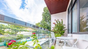A balcony with a glass railing, a potted plant, and a table with chairs.