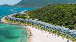 A resort with beachfront villas, a sandy beach, and a clear view of the ocean.