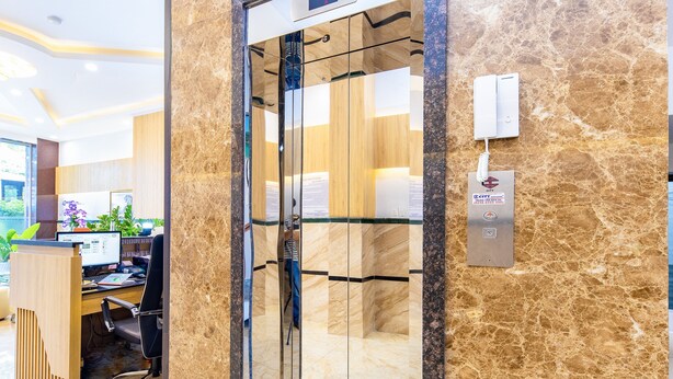 An elevator with a digital display, a reception desk with a computer, and a marble wall.
