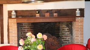 A fireplace with a brick surround, a wooden mantel, and a vase with flowers.