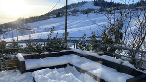 A snow-covered outdoor seating area with a view of a snowy landscape and houses in the background. - La Traverse, a large family home halfway between Gérardmer and La Bresse. (La Bresse)