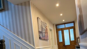 A hallway with a patterned tile floor, a wooden door with frosted glass panels, and a staircase with dark wood railings. - La Traverse, a large family home halfway between Gérardmer and La Bresse. (La Bresse)