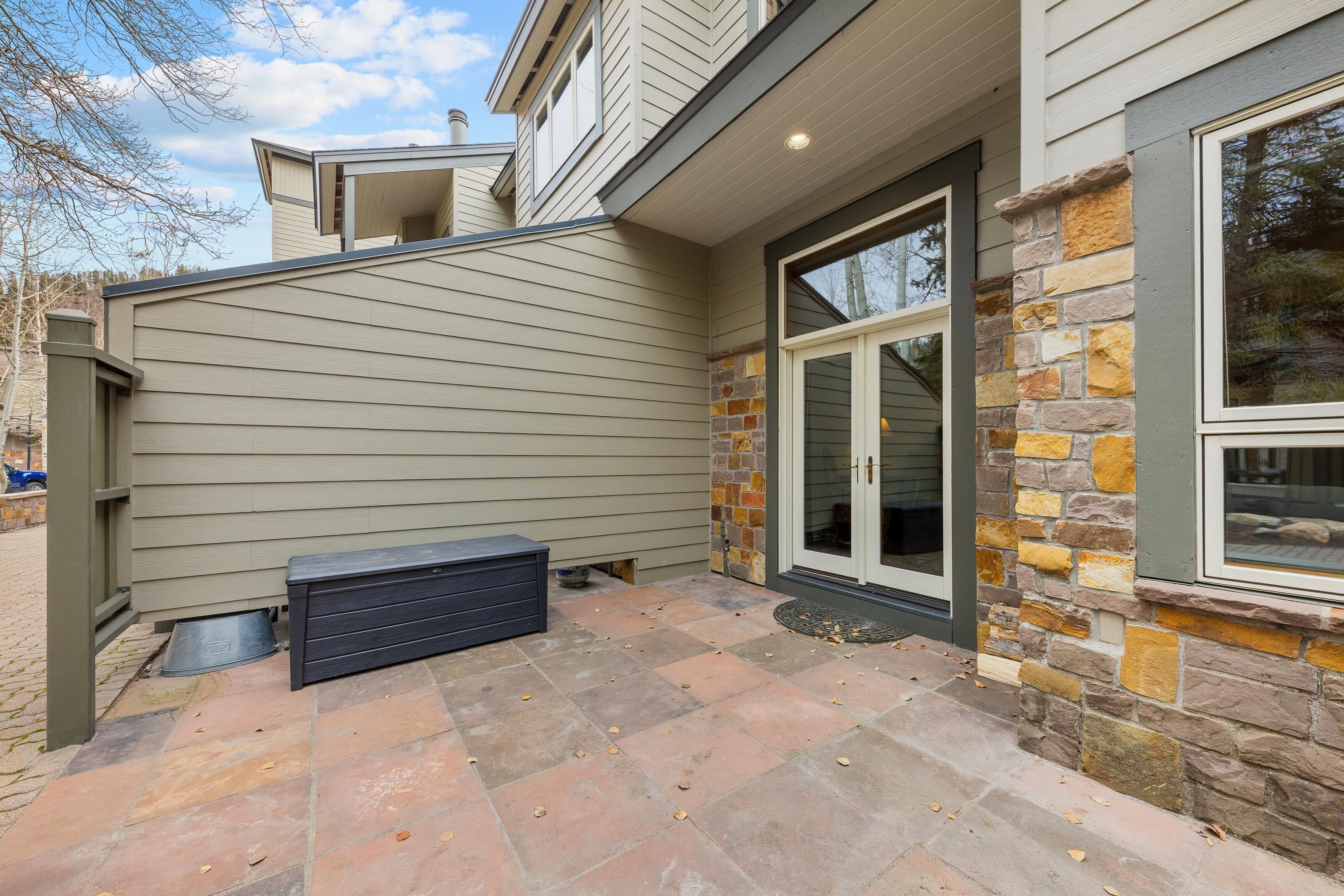 A house with a stone exterior, a sliding glass door, and a small outdoor bench.