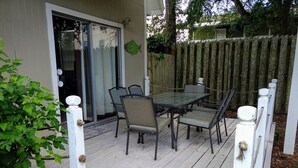 Un patio techado con una mesa y sillas, un ventanal corredero y una valla de madera.