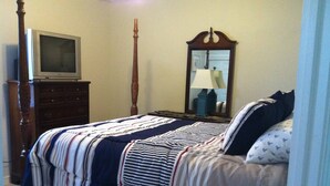 Un dormitorio con cama, cómoda, televisor y espejo.
