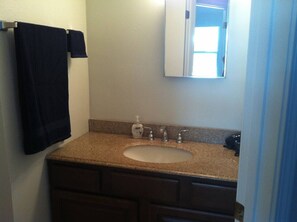 Un baño con lavamanos, espejo y perchero para toallas.